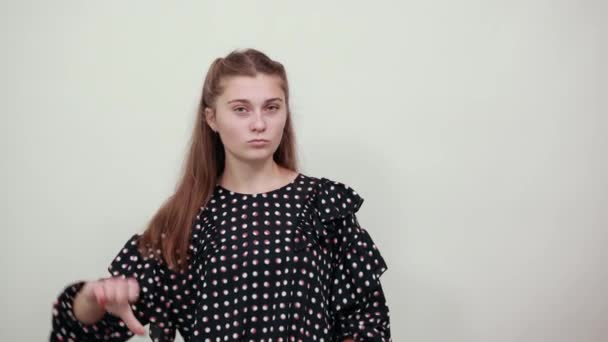 κορίτσι σε μαύρο φόρεμα με λευκούς κύκλους θυμωμένος εκνευρισμένη γυναίκα δίνει τους αντίχειρες κάτω - Πλάνα, βίντεο