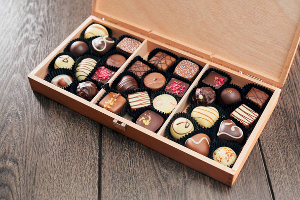 Different chocolate candies in wooden box. - Valokuva, kuva