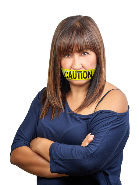 Angry brunette woman arm crossed with yellow caution tape on her mouth to shut and prevent she speaks her mind. Self control concept - Photo, Image