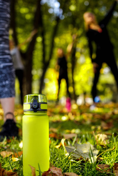 bottle of water on green grass. sporty women doing outdoor workout - Foto, Imagem