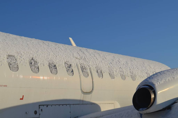 Большой пассажирский самолет полностью покрыт снегом сверху. Недавно прошла метель.
. - Фото, изображение