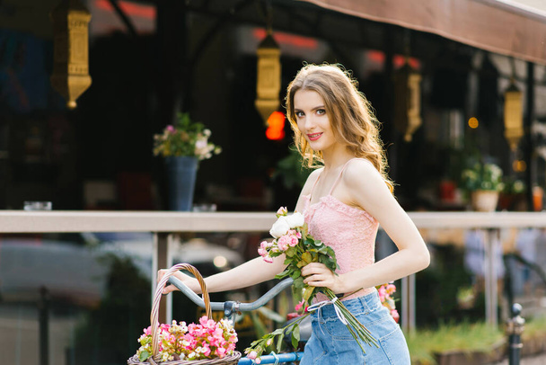 A beautiful young woman in a denim skirt and pink top walks thro - Zdjęcie, obraz
