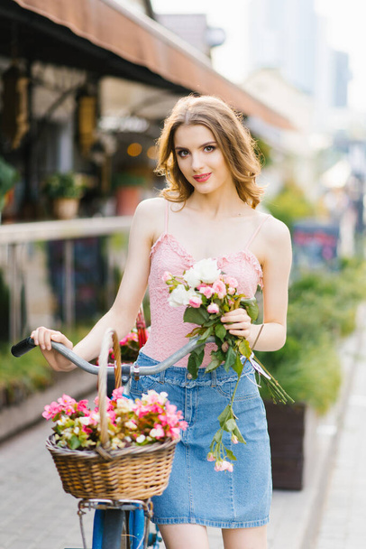 A beautiful young woman in a denim skirt and pink top walks thro - Photo, Image