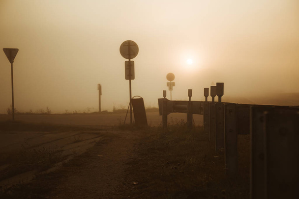 Znaki drogowe wzdłuż drogi. Wczesnym rankiem we mgle w drodze do pracy. Trasa turystyczna. - Zdjęcie, obraz