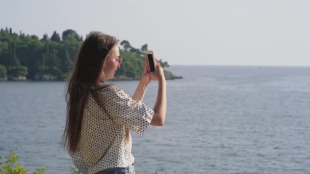 Dívka s mobilní přičemž malebné mořské záběry - Záběry, video