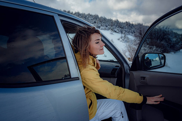 Giovane donna allegra in posa contro l'auto e la foresta di neve
. - Foto, immagini