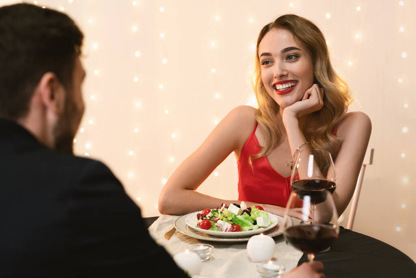 Νεαρό ζευγάρι στο εστιατόριο που έχει ρομαντικό δείπνο, απολαμβάνοντας χρόνο μαζί - Φωτογραφία, εικόνα