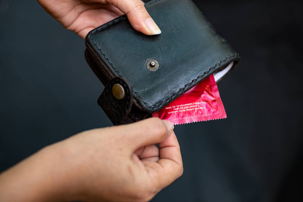 赤いコンドミニアム付きブラックレザー財布を保持する閉鎖女性の手 - 写真・画像