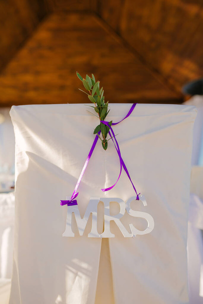 Sign "mrs" on the wedding chair and a sprig of greenery in the w - Photo, Image