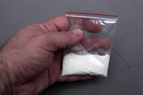 hombre sostiene bolsa de plástico en su mano con cocaína de cerca
 - Foto, Imagen