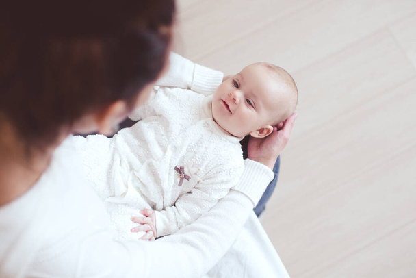 Happy baby 1 year old lying on mother hands in room. Looking at each other. Maternity. Motherhood.  - Fotoğraf, Görsel