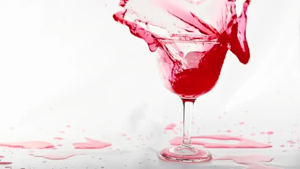 Jääkuutio putoaa roiskeella punaiseen tuoreeseen alkoholijuomaan valkoisella pohjalla, laukaus hidastettuna
. - Materiaali, video