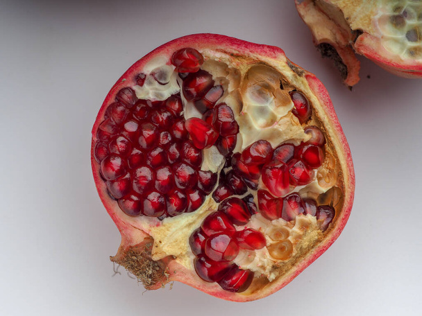 sliced ripe pomegranate with fruit kernels close up on a white background - Fotoğraf, Görsel