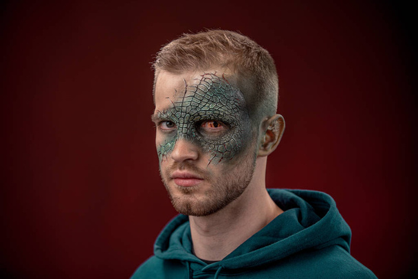 homme avec film d'horreur professionnel maquillage lézard vert sur fond rouge foncé. oeil de lézard
 - Photo, image