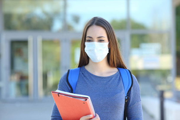 Student wearing a mask walking in a campus - 写真・画像