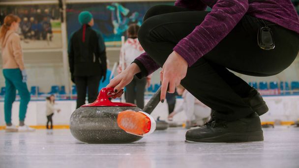 Curling školení - žulový kámen s červenou rukojetí - osoba stojící v blízkosti a držící curling kartáč - Fotografie, Obrázek