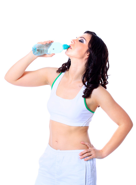 Young happy smiling woman in sportswear drinking water, isolated over white background - Foto, Bild