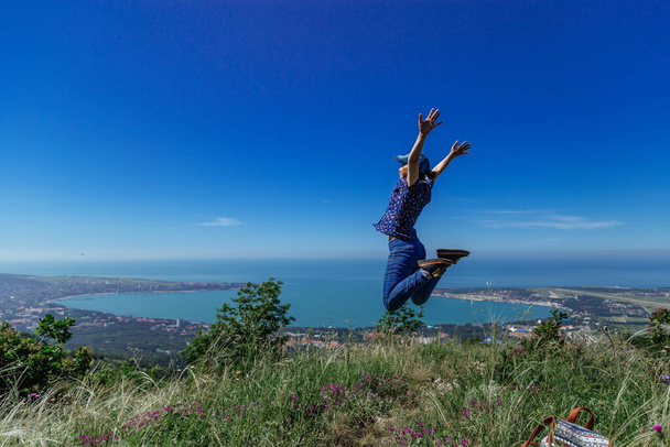 Girl jumps on the slope of a ridge.  Late spring (early summer)  - Фото, изображение