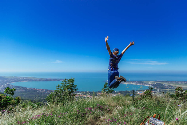 Girl jumps on the slope of a ridge.  Late spring (early summer)  - Foto, imagen