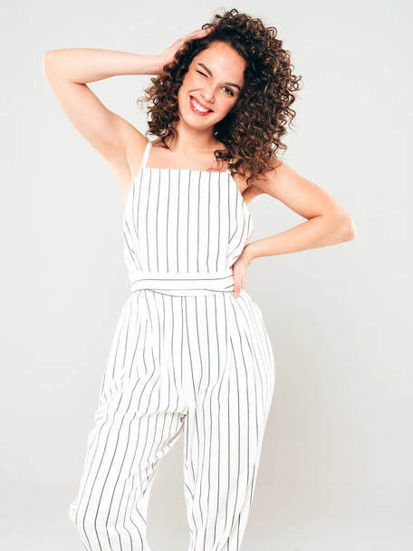 Portrait of beautiful smiling model with afro curls hairstyle dressed in summer hipster clothes.Sexy carefree girl posing in studio on gray background.Trendy funny and positive woman - Foto, Imagen