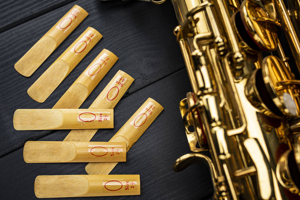Reeds of the mouthpiece of a sax next to the golden and shiny in - Fotografie, Obrázek
