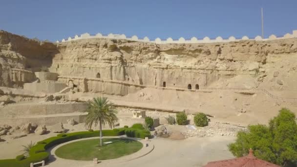 Khorbas Cave complex is located on the southern coast of the island of Keshm, Iran.The drone makes a video slowly flying up to the landmark from far away. You can see the caves in the rock, the fence, trees. - Footage, Video