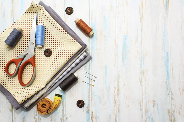 Sewing tools and fabric on a white background. Concept for needlework, stiching, embroidery and tiolori. Sewing multicolored threads, needles, ngpins, fabric, buttons and sewing centimeter. Top view, flatlay whith copy space. - 写真・画像