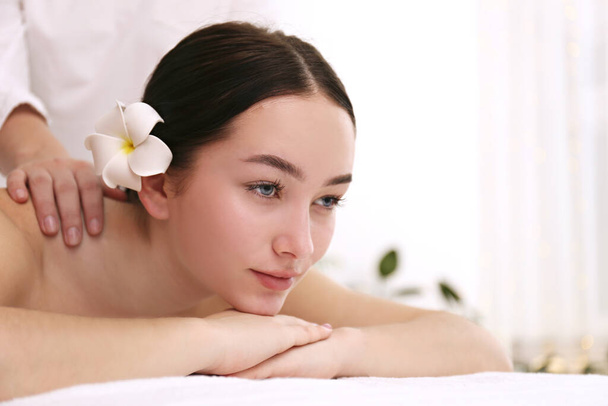 Brunette female with relaxed facial expression lying on a massage table. - 写真・画像