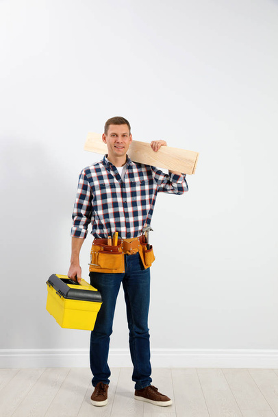 Handsome carpenter with wooden planks near light wall - Foto, immagini