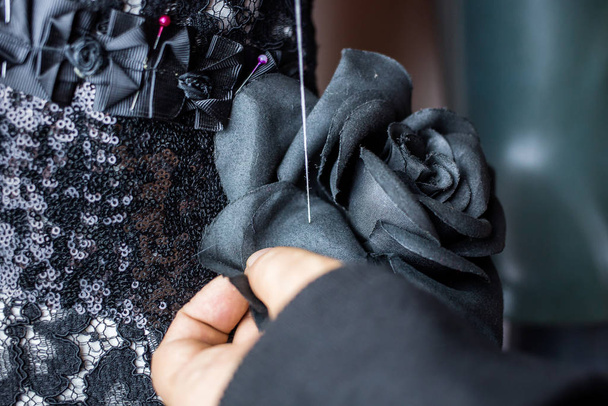 Fashion designer using needle to sew black fabric rose on top part of the dress. - Fotografie, Obrázek