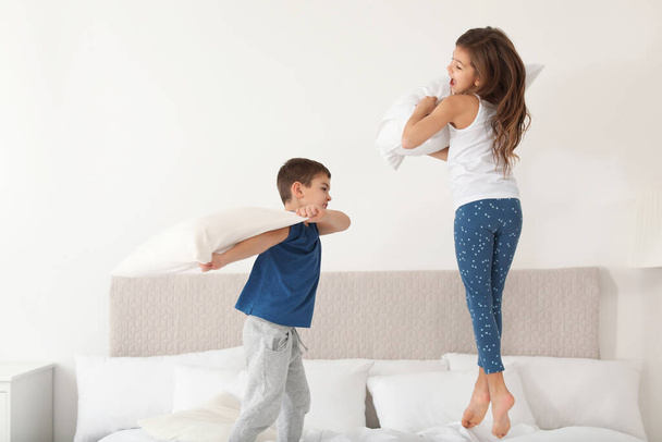 Happy children having pillow fight in bedroom - Fotoğraf, Görsel