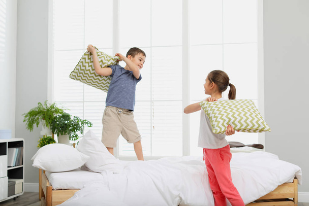 Happy children having pillow fight in bedroom - Valokuva, kuva