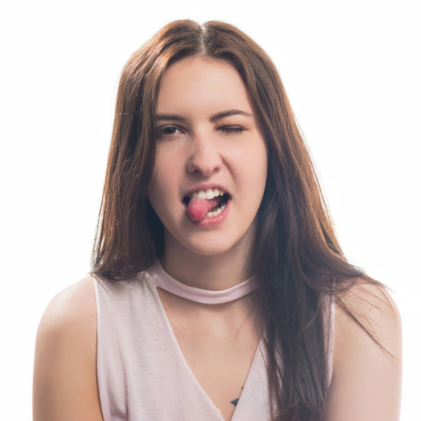 young brunet woman teasing portrait with tongue out  tisolated on white background - Foto, Bild