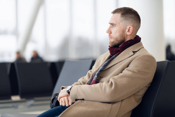 Üzletember ül a repülőtér várótermében, és várja a járatot. Férfi vezető a repülőtér üzleti társalgóban ül a váróteremben. - Fotó, kép