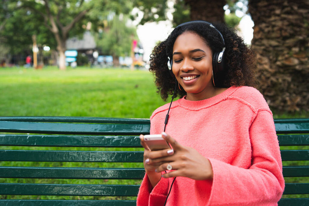 Afro-American woman listening music with phone. - Foto, imagen