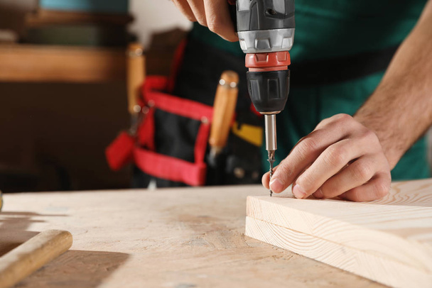 Professional carpenter twisting screw with drill at workbench, closeup. Space for text - Fotoğraf, Görsel