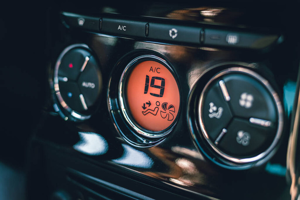 Hands of woman turning car air conditioning system. Button on dashboard to cold air in new car - orange panel. Photo of climate control view with air conditioning button with celsius degrees - 19. - Photo, Image