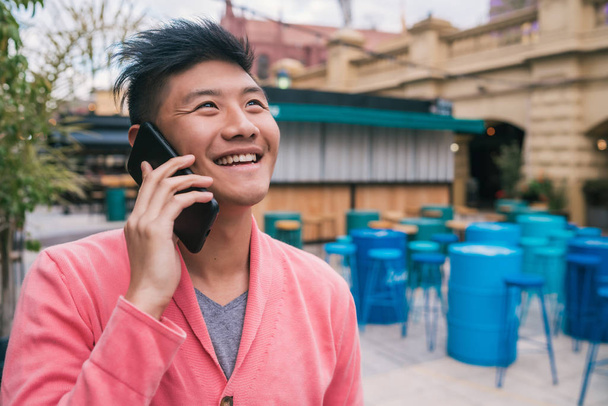 Asian man talking on the phone outdoors. - Valokuva, kuva