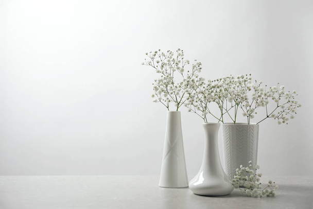 Gypsophila flowers in vases on table against white background. Space for text - Foto, Imagem