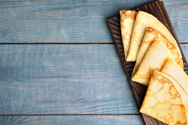 Fresh thin pancakes on blue wooden table, top view. Space for text - Foto, imagen