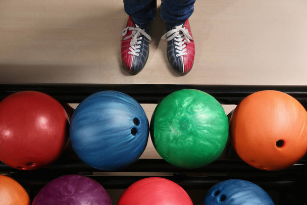 Person in bowling shoes near rack with balls, top view - Foto, Imagem
