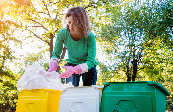 Volunteer girl sorts garbage in the street of the park. Concept of recycling.  - Photo, image