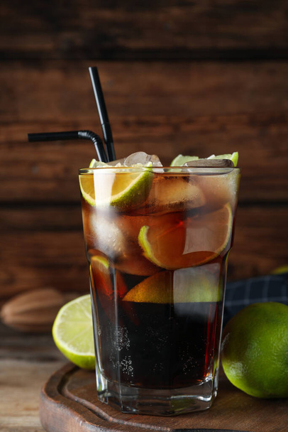 Glass of fresh Cuba Libre cocktail on wooden table, closeup - Foto, afbeelding