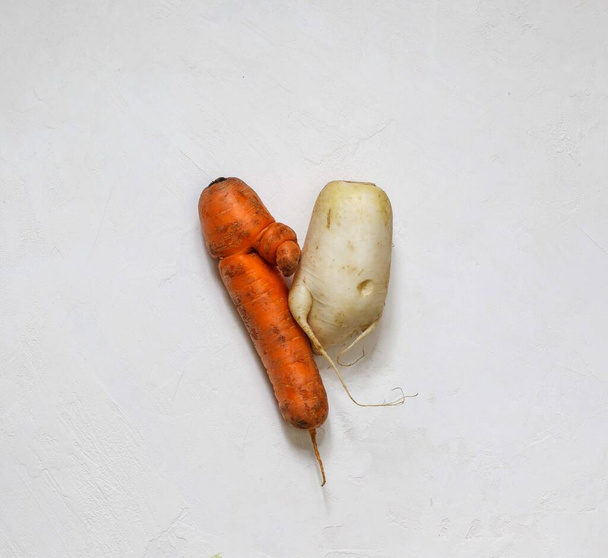 Ruma porkkana ja daikon retiisi sydämen muodossa valkoisella pohjalla
 - Valokuva, kuva
