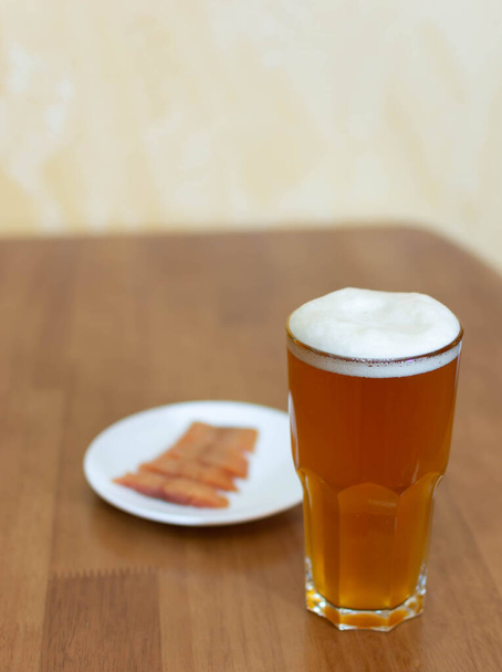 Cerveza en un vaso sobre la mesa y un plato con pescado
 - Foto, imagen