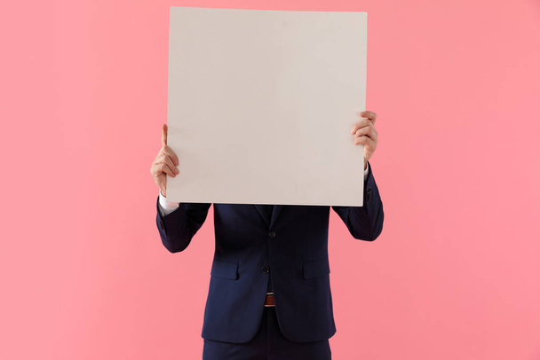 Joven hombre de negocios cubriéndose la cara con un cartel en blanco
 - Foto, Imagen