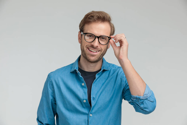 confident young model smiling and fixing glasses - Foto, Bild