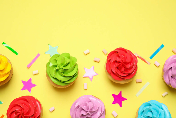 Colorful birthday cupcakes on yellow background, flat lay. Space - Fotó, kép