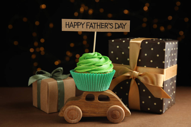 Composition with cupcake and gift boxes on brown table against blurred lights. Happy Father's day - Foto, Bild