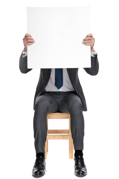 młody biznesmen przykrywający twarz pustą deską - Zdjęcie, obraz